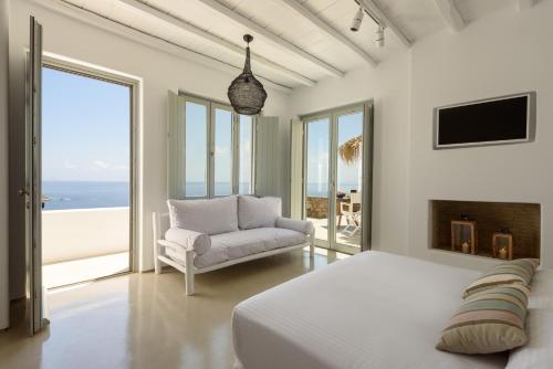 a bedroom with a bed and a couch and the ocean at The Summit of Mykonos in Kalo Livadi