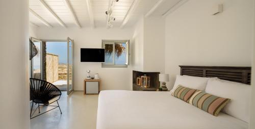 a white bedroom with a large bed and a television at The Summit of Mykonos in Kalo Livadi