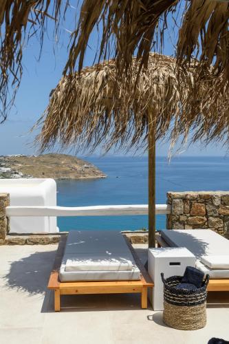 a patio with a bed and a view of the ocean at The Summit of Mykonos in Kalo Livadi