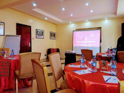 a meeting room with tables and chairs and a screen at Falcon Heights Hotel in Nanyuki