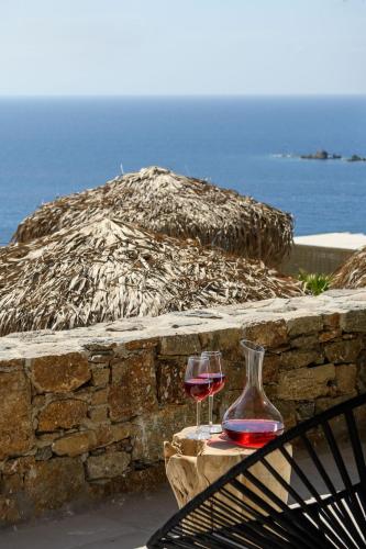 two wine glasses sitting on a table next to a stone wall at The Summit of Mykonos in Kalo Livadi