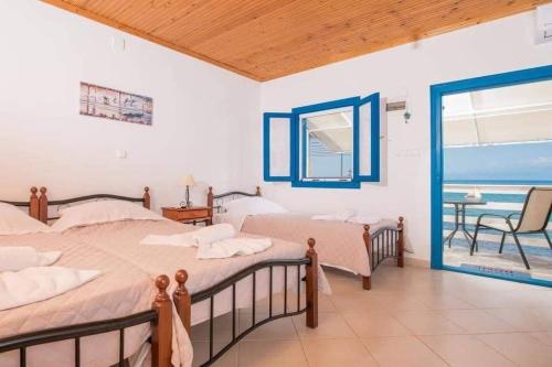 two beds in a room with a view of the ocean at Julie's Hermes house in Skala Kallirachis