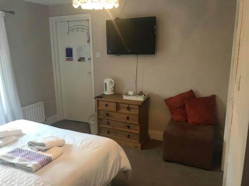 a bedroom with a bed and a chair and a flat screen tv at The Shepherd's Rest in Alnwick