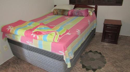 ein Bett mit einer bunten Decke und einem Nachttisch in der Unterkunft Casa Linda e Arejada in São Thomé das Letras