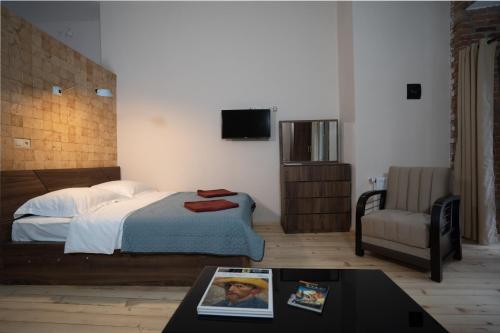 a bedroom with a bed and a chair and a table at Wine Inn Borjomi Aparthotel in Borjomi