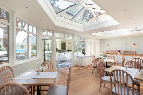 a dining room with tables and chairs and windows at Villa Sedina in Rewal