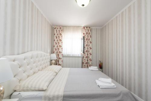een witte slaapkamer met een groot wit bed en een raam bij Castua-apartment with private heated pool in Kastav