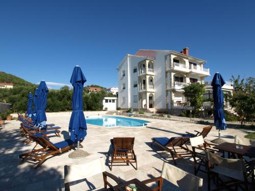 ein Pool mit Stühlen und Sonnenschirmen sowie ein Gebäude in der Unterkunft Apartments Villa Olga in Rab