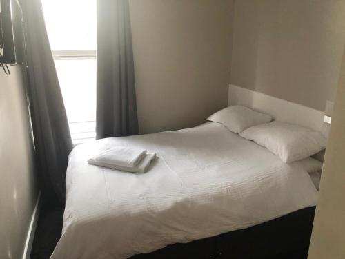 a bed with two white towels on top of it at The Fulwich Hotel in Dartford