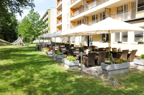 un patio del hotel con mesas, sillas y una sombrilla en Hotel Garni, en Považská Bystrica