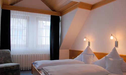 a hotel room with two beds and a chair at Hotel Gülser Weinstube in Koblenz