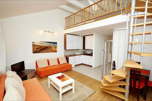 a living room with an orange couch and a staircase at Apartamenty Międzymorzem in Krynica Morska
