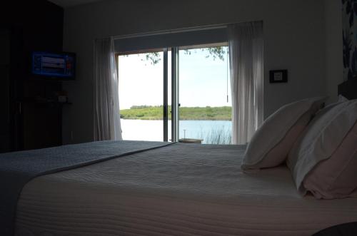 a bedroom with a large bed with a large window at Al Natural Posada in Nueva Palmira