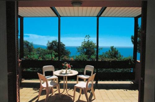 um pátio com uma mesa e cadeiras e vista para o oceano em Residence Pianeta Maratea em Maratea