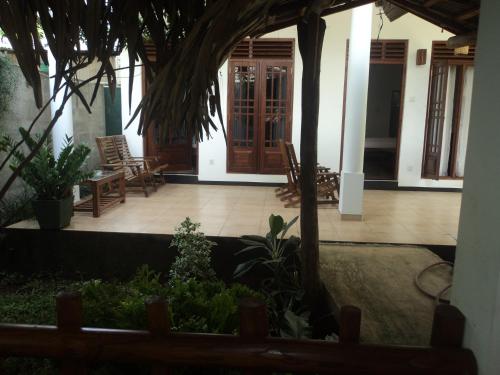 a house with a courtyard with chairs and trees at Baby Elephant Green House in Udawalawe