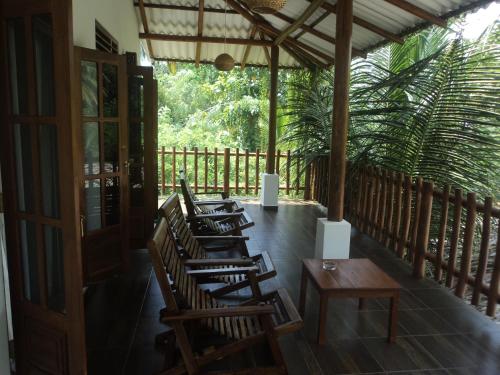 a row of wooden chairs and tables on a porch at Baby Elephant Green House in Udawalawe