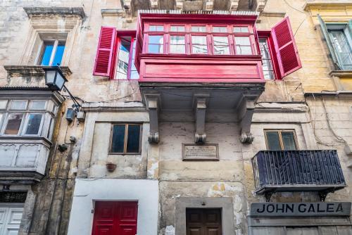 an old building with red doors and windows at Valletta Kampnar City Living in Valletta