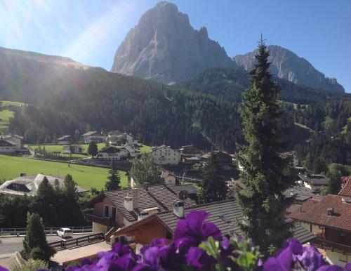a view of a village in the mountains with purple flowers at Appartamenti Olympic in Santa Cristina in Val Gardena