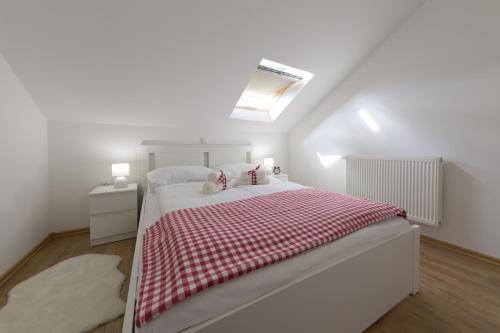 a white bedroom with a bed with a red and white blanket at House Smolčić in Otočac