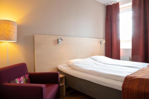 a hotel room with a bed and a chair at Hotell Vilja in Umeå