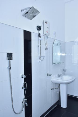 a white bathroom with a shower and a sink at Baby Elephant Green House in Udawalawe
