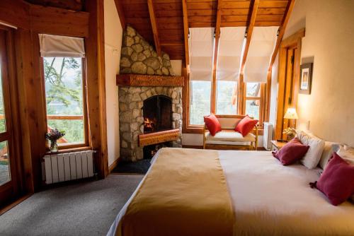 1 dormitorio con 1 cama grande y chimenea en Amigos del Bosque en Villa La Angostura