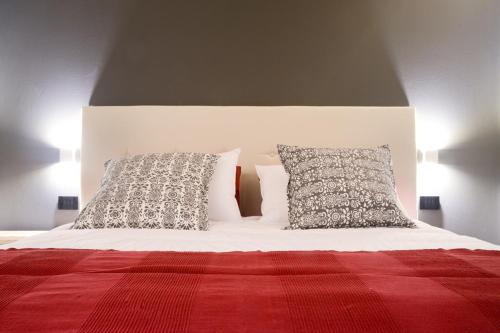 a bed with two pillows and a red blanket at Hotel san Vitale in Bormio