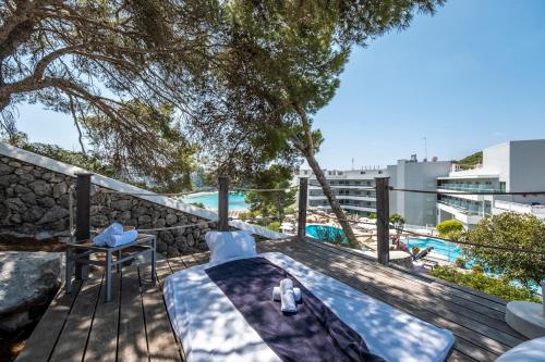 a deck with a table and chairs and a pool at ARTIEM Audax - Adults Only in Cala Galdana
