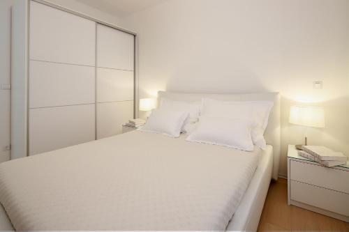 een witte slaapkamer met een groot wit bed met witte kussens bij Modern apartment near the sea in Ičići