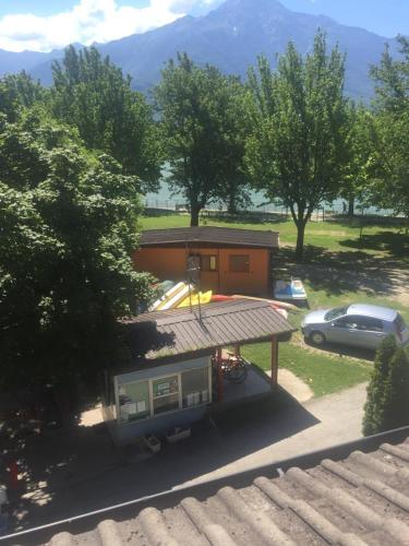 a house with a trailer in a parking lot with a car at Camping Hotel Au Lac De Como in Sorico