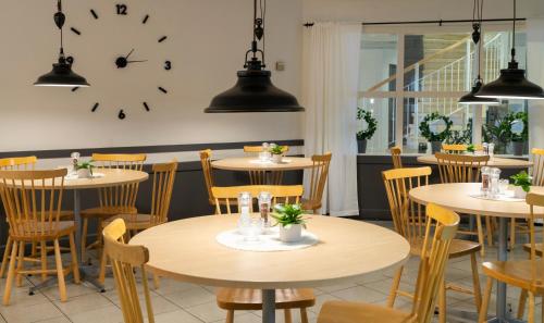 a restaurant with tables and chairs and a clock on the wall at Hotell Vilja in Umeå