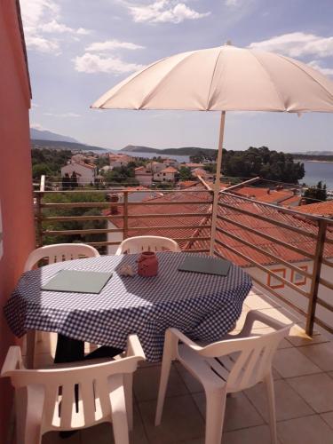 a table and chairs with an umbrella on a balcony at Apartments Aleksandra in Rab