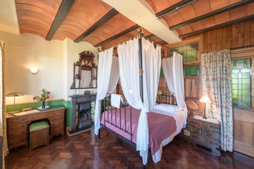La Flamenca Inn في Cortelazor: غرفة نوم مع سرير المظلة ومدفأة