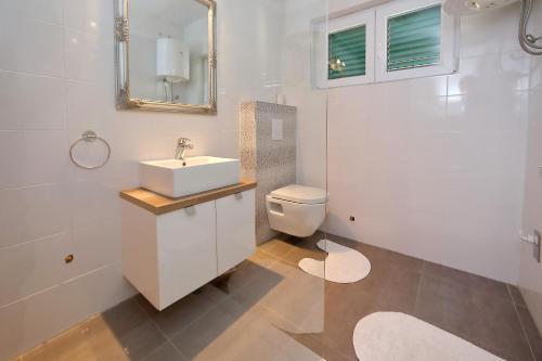a white bathroom with a sink and a toilet at Sara in Bibinje