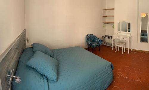 een slaapkamer met een blauw bed en een bureau bij Appartement l’étoile in Moustiers-Sainte-Marie