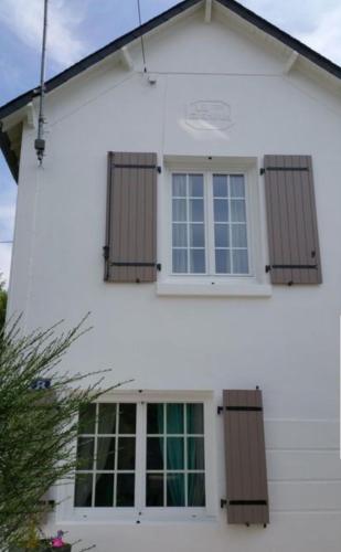 een wit huis met bruine luiken erop bij Maison carnac plage in Carnac