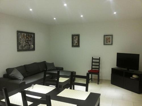 een woonkamer met een bank, stoelen en een tv bij PIETROSELLA Plage du RUPIONE in Pietrosella