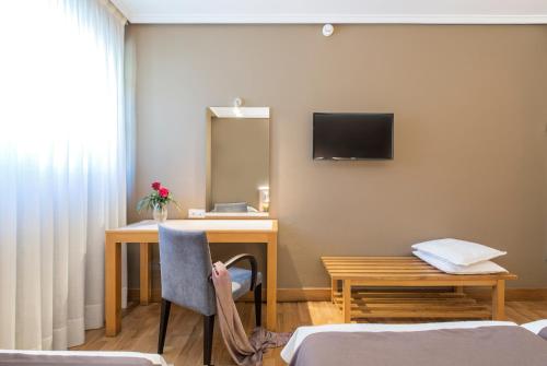 a hotel room with a desk and a tv on the wall at La Casa del Patrón in Murguía