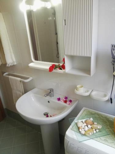biała łazienka z umywalką i lustrem w obiekcie appartamento con vista piscina w mieście San Teodoro