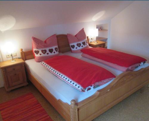 una camera da letto con un grande letto con lenzuola e cuscini rossi di Ferienwohnung Steible a Isny im Allgäu