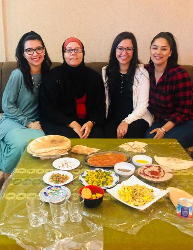 a group of women sitting around a table with food at Petra View Flat in Wadi Musa