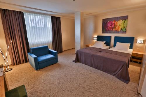 Terra Europe Brontes Hotel في تارغوفيشته: غرفه فندقيه بسرير وكرسي ازرق