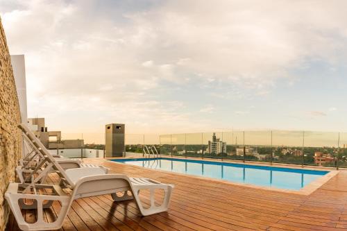 a deck with chairs and a swimming pool on a building at Realty PY Saravi in Asuncion