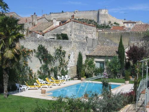 a villa with a swimming pool in front of a castle at Les Jardins De La Livrée in Villeneuve-lès-Avignon