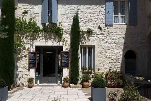 a white stone building with a door and a tree at Les Jardins De La Livrée in Villeneuve-lès-Avignon