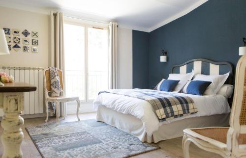 1 dormitorio con cama y pared azul en Les Jardins De La Livrée, en Villeneuve-lès-Avignon