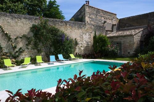 a swimming pool with chairs and a building at Les Jardins De La Livrée in Villeneuve-lès-Avignon