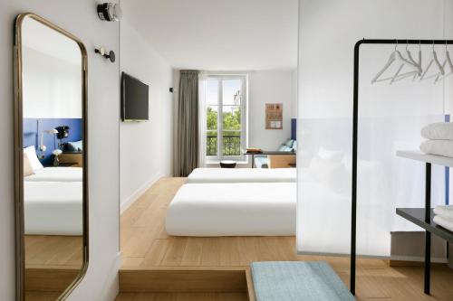 a bedroom with two beds and a mirror at Oh la la ! Hotel Bar Paris Bastille in Paris