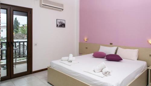 a bedroom with a large white bed with purple pillows at Yannis Apartments in Afitos