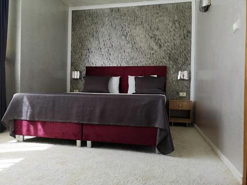 a bedroom with a large bed with a red headboard at Terra Europe Brontes Hotel in Targovishte